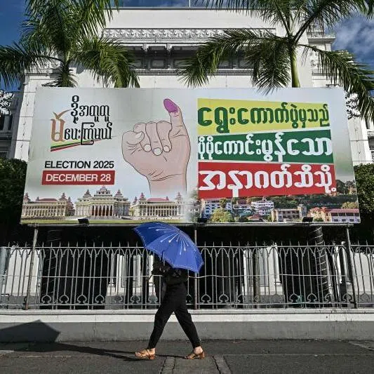 A woman walking past an election banner during the first phase of Myanmar's general election in Yangon on Dec 28.