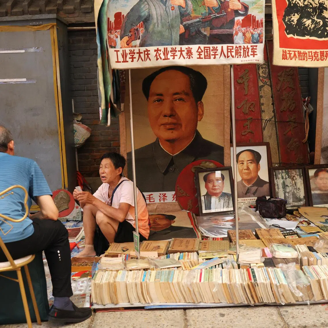 FILE PHOTO: A vendor attends to a customer next to images and statues depicting late Chinese chairman Mao Zedong, at the secondhand books section of Panjiayuan antique market in Beijing, China August 3, 2024. REUTERS/Florence Lo/File photo