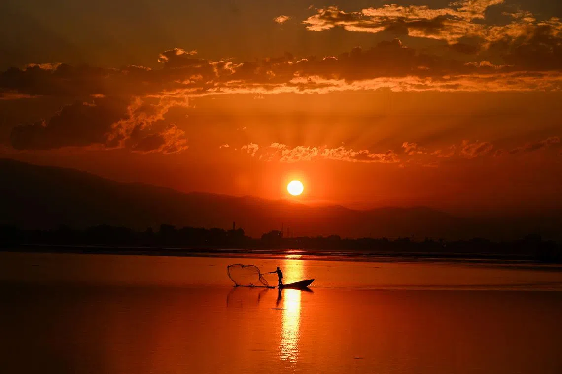 A fisherman casting his net in Dal Lake during sunset in Srinagar on Sept 28.
