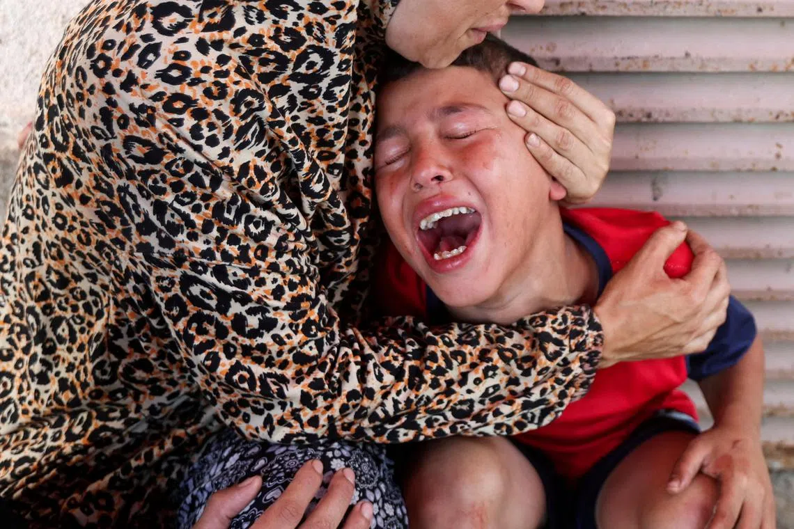A Palestinian woman comforts her son after her daughter was killed in an Israeli strike near a medical centre in Gaza.