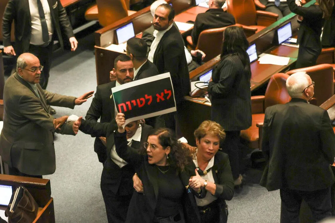 Knesset member Naama Lazimi holds a banner reading "do not cover up", as she is escorted out by Knesset ushers during a debate on the Oct 7 investigation Bill on Dec 24.