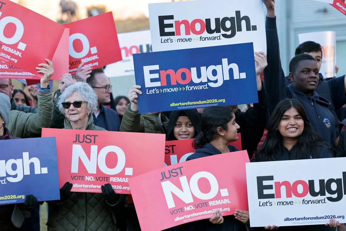 Volunteers at Bridgeland Riverside Community Association Park hold placards for Alberta’s referendum in Calgary, Canada, on Oct 15.