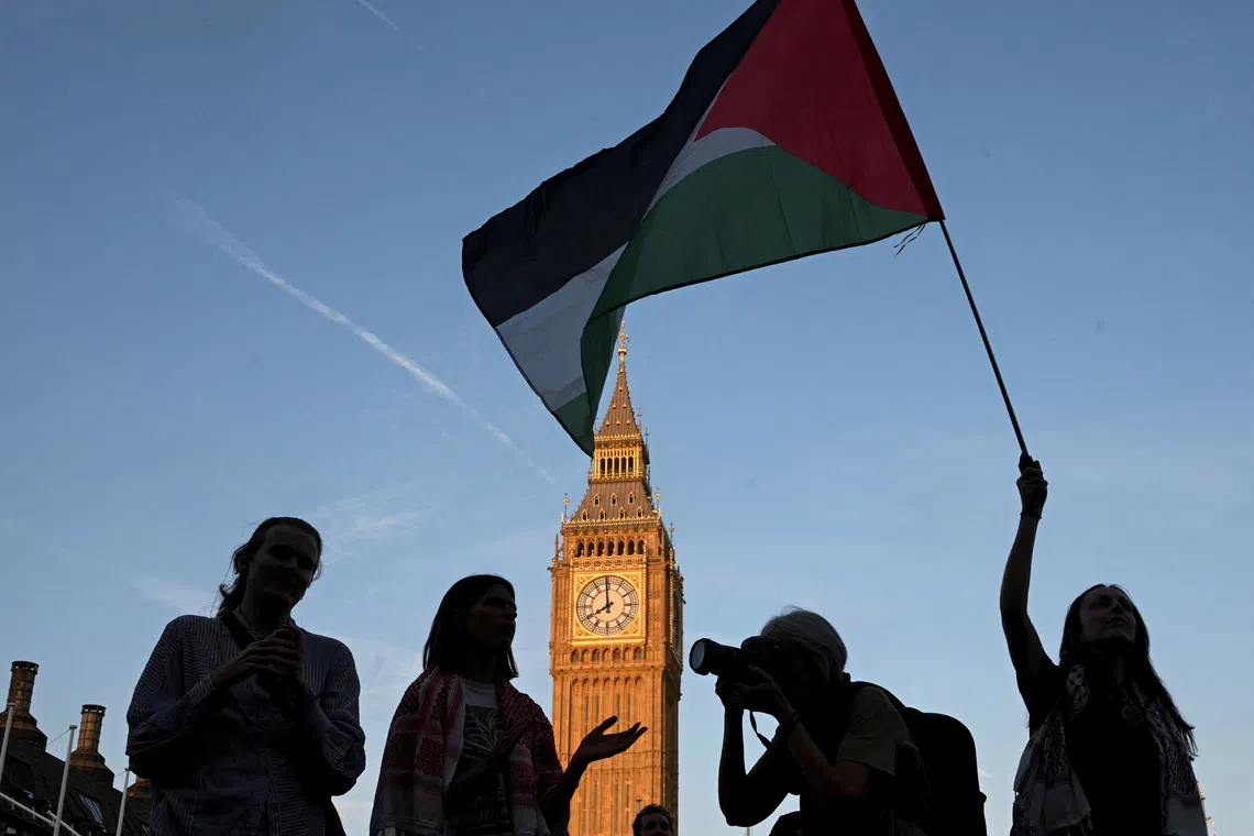 FILE PHOTO: A woman holds a Palestinian flag as demonstrators attend a rally organised by Defend Our Juries, challenging the British government's proscription of \"Palestine Action\" under anti-terrorism laws, in Parliament Square, in London, Britain, August 9, 2025. REUTERS/Jaimi Joy/ File Photo