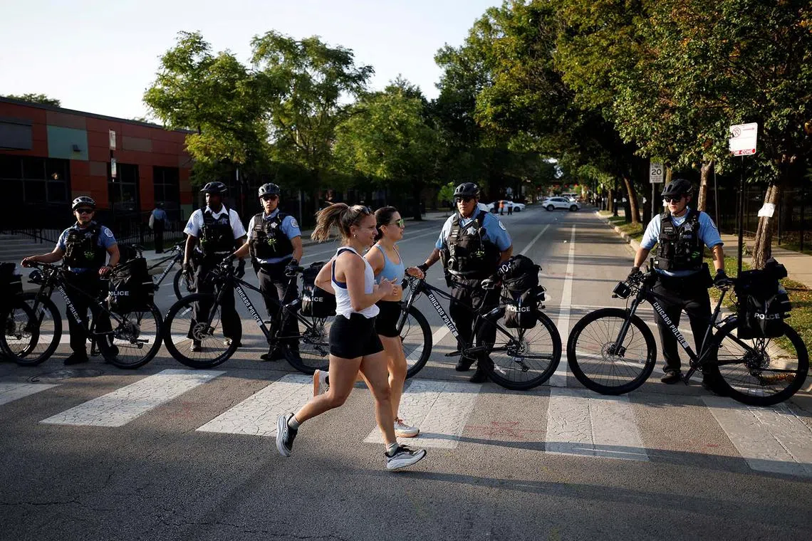 Women jog as police officers block a road during a protest in support of Palestinians in Gaza, amid the Israel-Hamas conflict, on the sidelines of the Democratic National Convention (DNC), in Chicago, Illinois, U.S., August 21, 2024. REUTERS/Marco Bello TPX IMAGES OF THE DAY