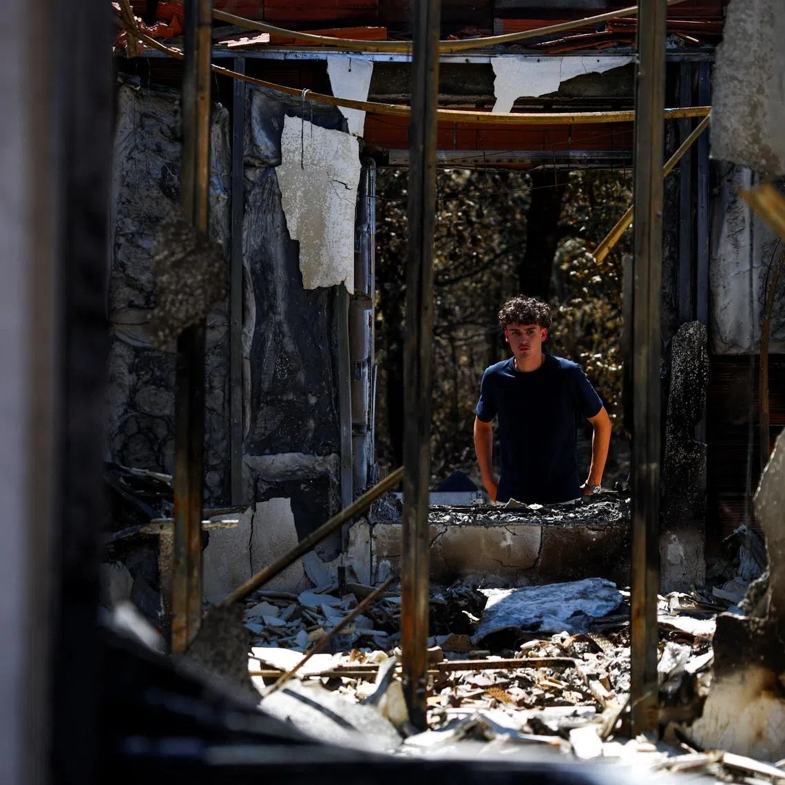 Raphael Fohanno, 18, looks at his burnt family home near a forest affected by a wildfire, in Biscarrosse, Landes department, amid drought conditions, a new heatwave warning, and water shortages across much of France, July 28, 2026. REUTERS/Sarah Meyssonnier