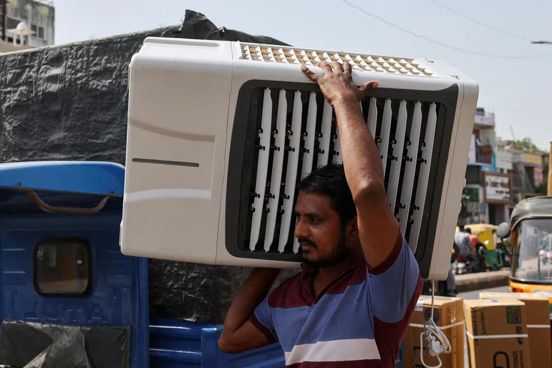 FILE PHOTO: A worker carries an air cooler for delivery to a customer during the heat wave in Ahmedabad, India, May 30, 2024. REUTERS/Amit Dave/File Photo