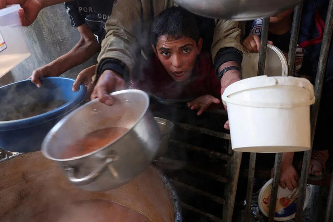 FILE PHOTO: A Palestinian child reacts, while people gather to get their share of charity food offered by volunteers, amid food shortages, as the conflict between Israel and the Palestinian Islamist group Hamas continues, in Rafah, in the southern Gaza Strip, December 2, 2023. REUTERS/Ibraheem Abu Mustafa/File Photo