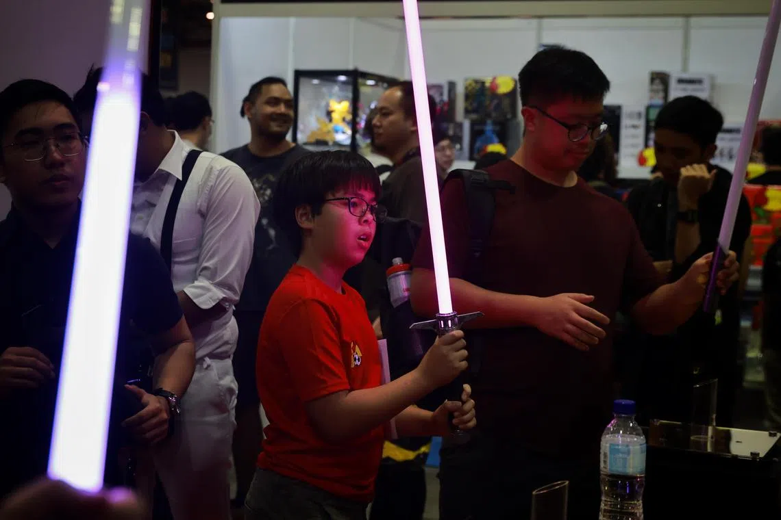 Visitors looking at combat lightsabers made by home-grown lightsaber-maker Sabermach at the Sands Expo & Convention Centre on Sunday (Dec 11, 2022). 
