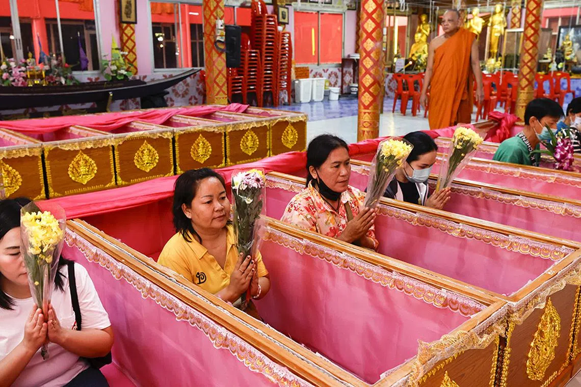 epa11801130 Thai people pray inside coffins as a Buddhist monk performs a rite during the New Year's resurrection ceremony at Wat Takien temple in Nonthaburi province, on the outskirts of Bangkok, Thailand, 01 January 2025. The resurrection ceremony rituals are performed at a Buddhist temple where Thai devotees lie in coffins symbolizing the concepts of death and rebirth in hopes of ushering in a new year filled with luck and the fulfillment of their wishes.  EPA-EFE/RUNGROJ YONGRIT
