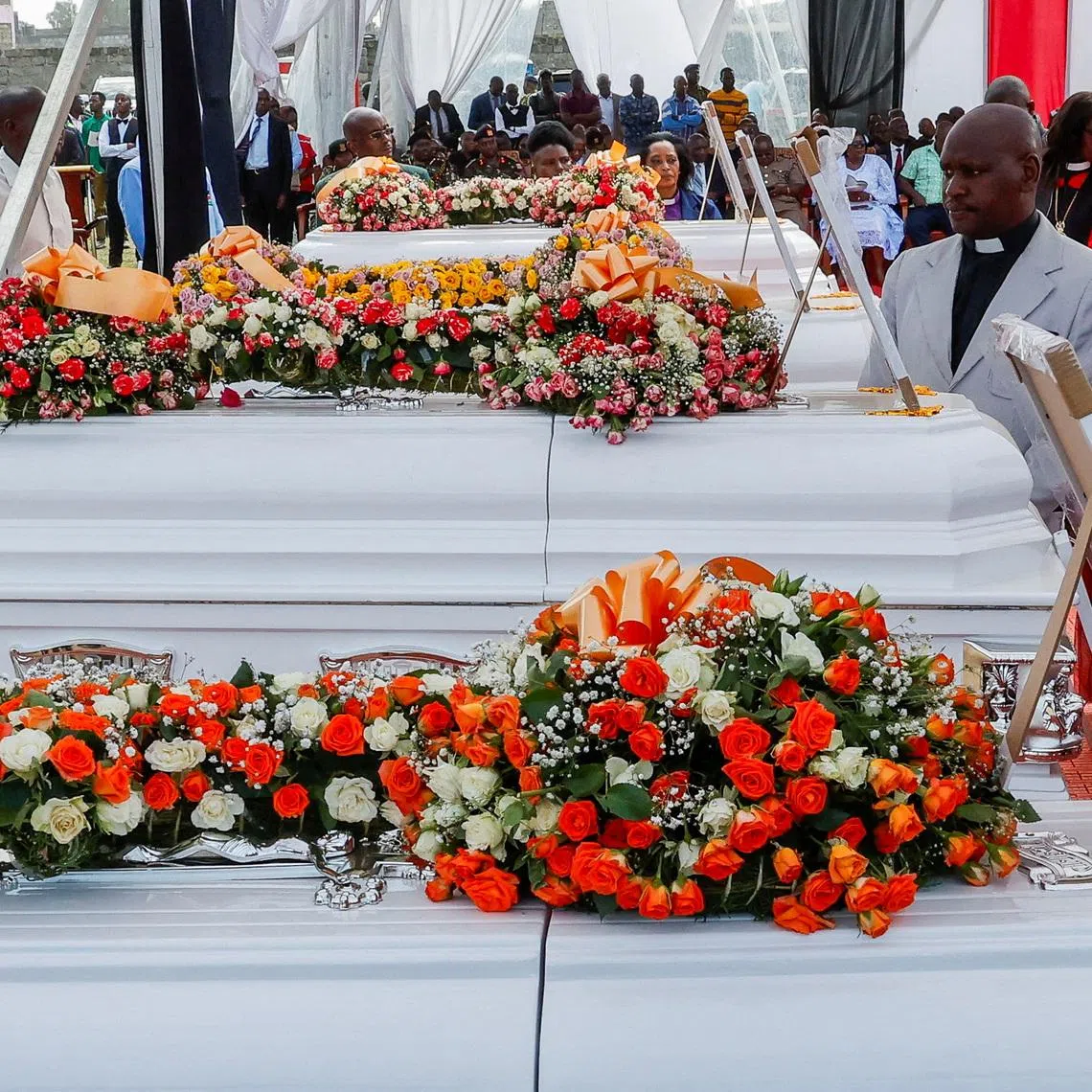 FILE PHOTO: Members of the clergy stand next to coffins of victims of an overnight dormitory fire at the Utumishi Girls Academy Senior School, during a memorial service at the Gilgil Stadium, in Gilgil, Nakuru county, Kenya, June 12, 2026. REUTERS/Monicah Mwangi/File Photo