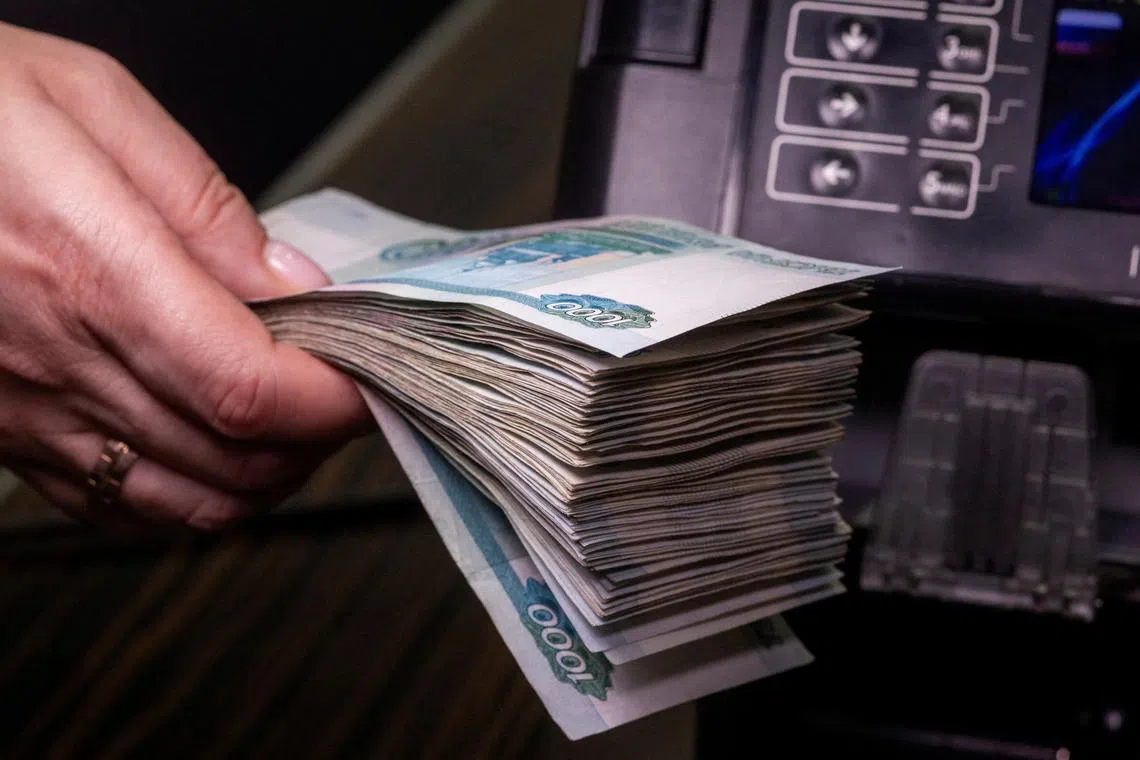 FILE PHOTO: An employee holds Russian 1000-rouble banknotes next to a currency counting machine in a bank office in Moscow, Russia, in this illustration picture taken October 9, 2023. REUTERS/Maxim Shemetov/Illustration/File Photo