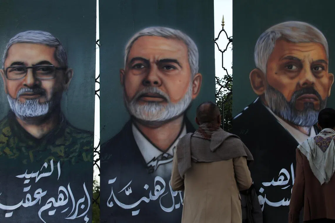 Passers-by in Sana’a, Yemen, look at paintings of Hezbollah leaders taken out by Israel.