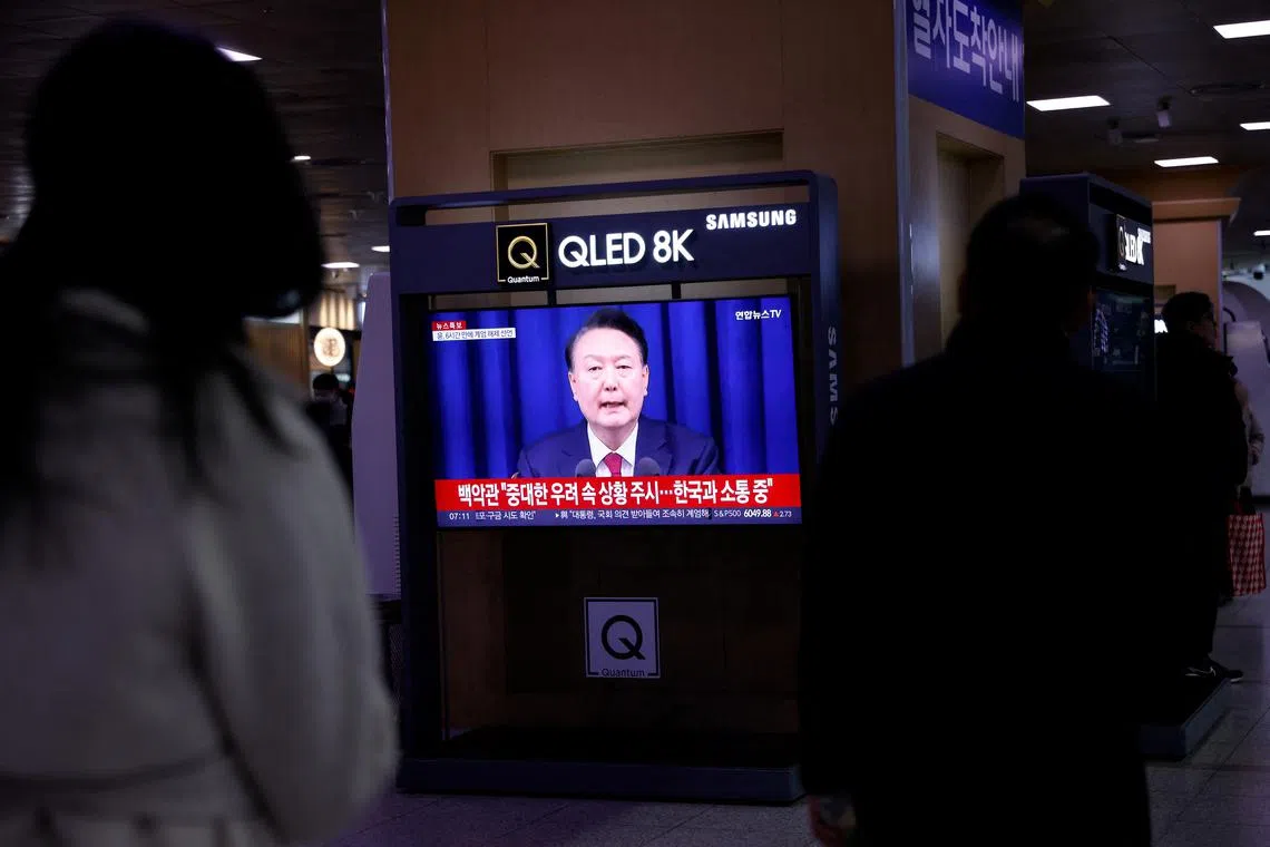 People watch a news report on President Yoon Suk Yeol's declaration of martial law in Seoul, on Dec 4.