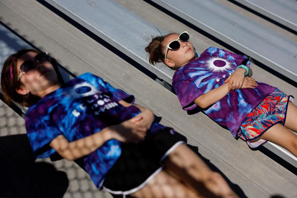 Ximena 7 and Magdalena Govea 11 lie down at Saluki Stadium, ahead of a total solar eclipse, where the moon will blot out the sun, in Carbondale, Illinois, U.S. April 8, 2024. REUTERS/Evelyn Hockstein     TPX IMAGES OF THE DAY     