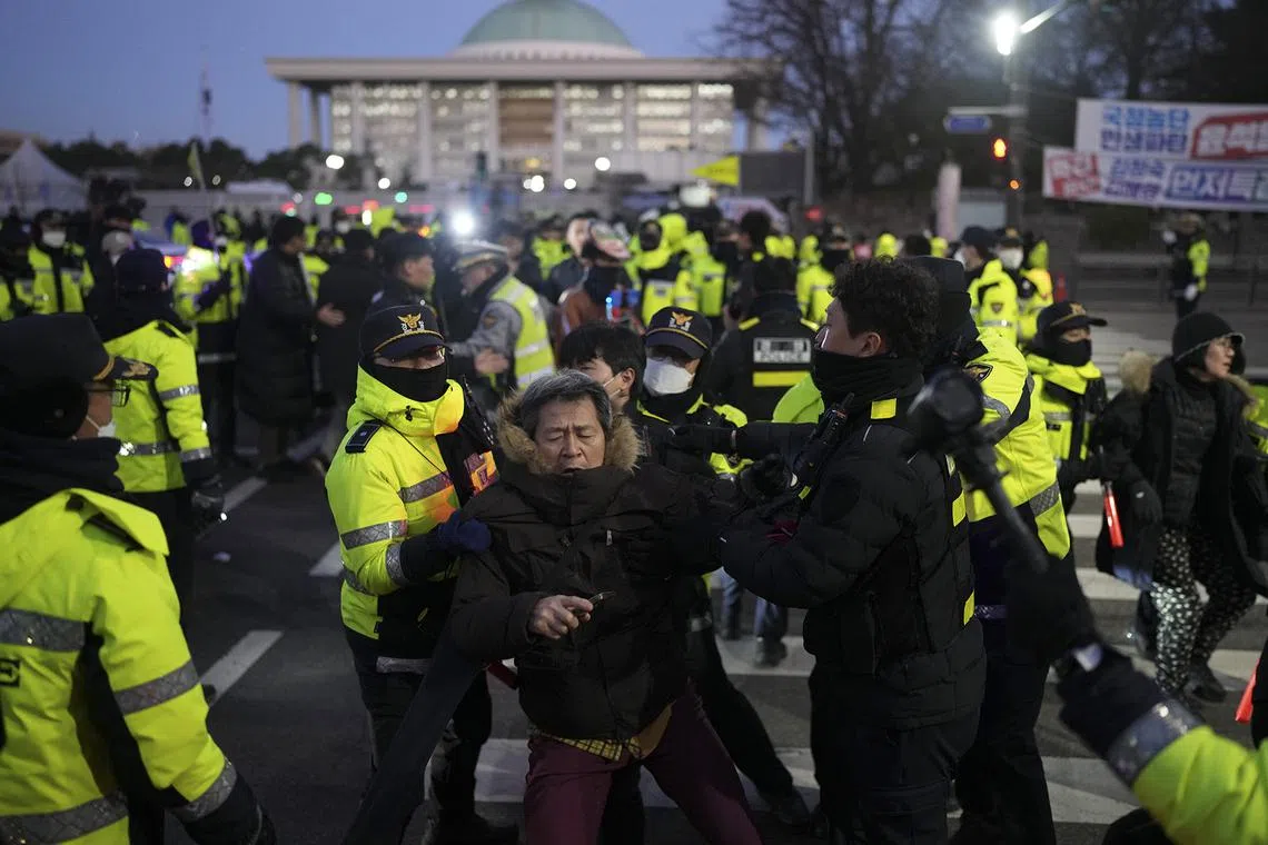Police officers scuffling with a man near the main gate to the National Assembly building in Seoul, on Dec. 4, 2024. 