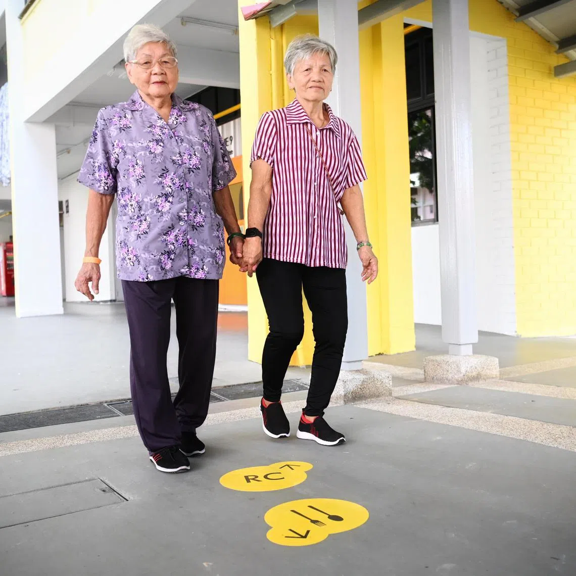 Madam Pek Eng (left) and her daughter, Madam Ng Pang Hoi, walking by the wayfinding markers on the ground near  Block 646 Ang Mo Kio Ave 6.