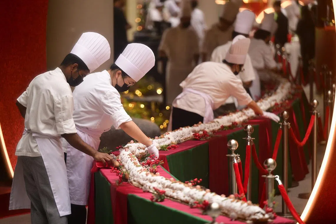 ST20241218_202487200196 pixstollen18 Azmi Athni// 50 kitchen staff from Resorts World Sentosa (RWS) doing their final preparation for the longest Stollen bread in Singapore before its adjudication by Singapore Book of Records on Dec 18. The official length of the 500kg festive treat is 93.1 meters. Stollen is a sweet bread filled with fruits, nuts, and spices, typically served during Christmas. Over the past three months, the RWS kitchen staff, led by their bakery sous chef Jude Anthony Danker, have prepared 293 pieces of Stollen, each 30cm long, for their record-breaking attempt.  ST PHOTO: AZMI ATHNI