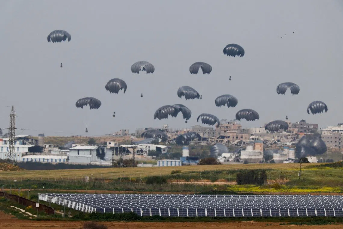 Humanitarian aid falls through the sky towards the Gaza Strip after being dropped from an aircraft.   