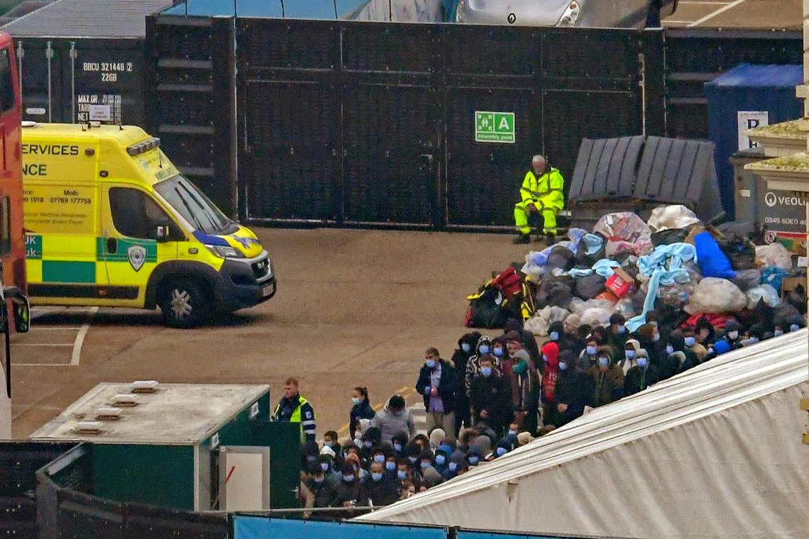 People, believed to be migrants, queue to board a bus after they were picked up in the English Channel by British Border Force and brought back to Dover, Britain, November 14, 2022. 