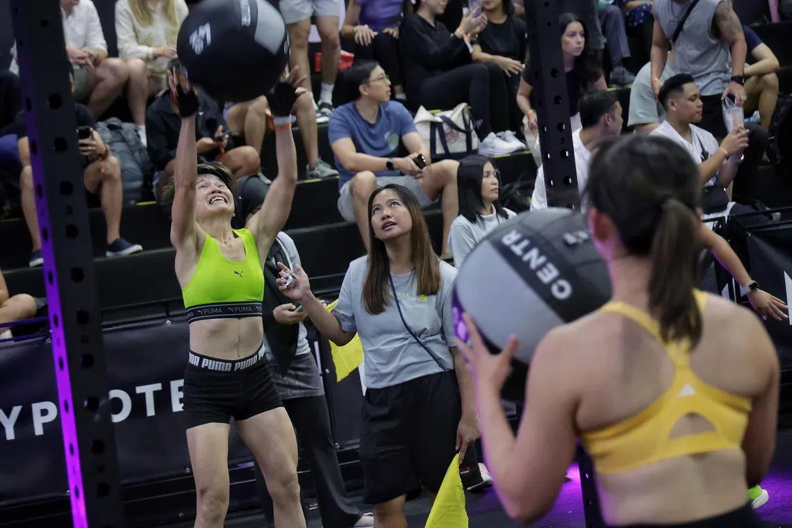 Ms Stella Eng (in neon yellow top), 55, exercise trainer with Khoo Teck Puat Hospital, overcoming the final station of wall balls during the Hyrox women's open at Singapore Expo on Sep 1, 2024.