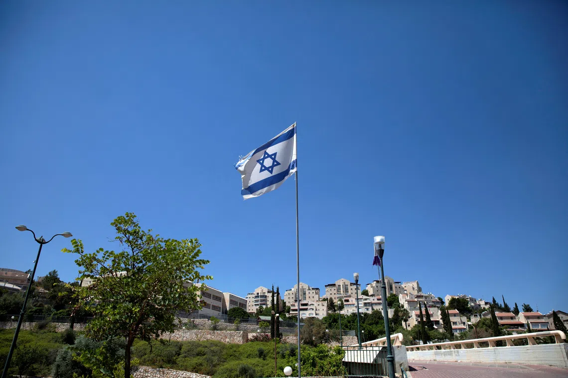 FILE PHOTO: The Israeli national flag flutters as apartments are seen in the background in the Israeli settlement of Maale Adumim in the Israeli-occupied West Bank August 16, 2020. Picture taken August 16, 2020. REUTERS/Ronen Zvulun/File Photo