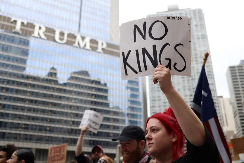 A demonstrator holds a sign in front of Trump International Hotel and Tower, as people gather for a "No Kings" protest in Chicago, Illinois, USA.