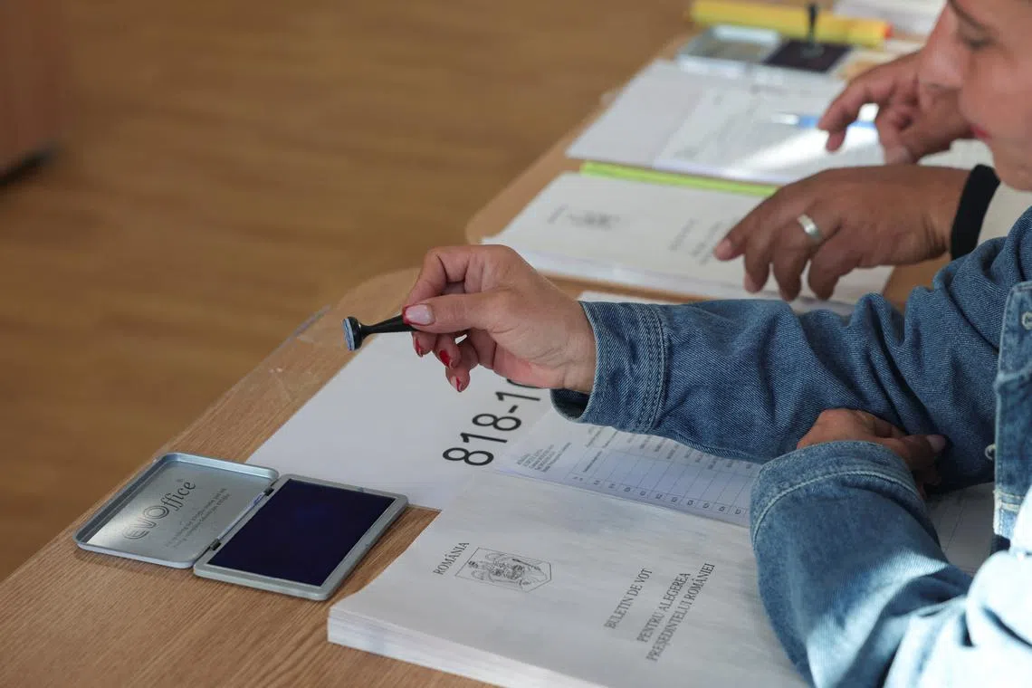 Electoral workers sit at a polling station during Romania's first round of presidential election, in Mogosoaia, Romania, May 4, 2025. REUTERS/Louisa Gouliamaki