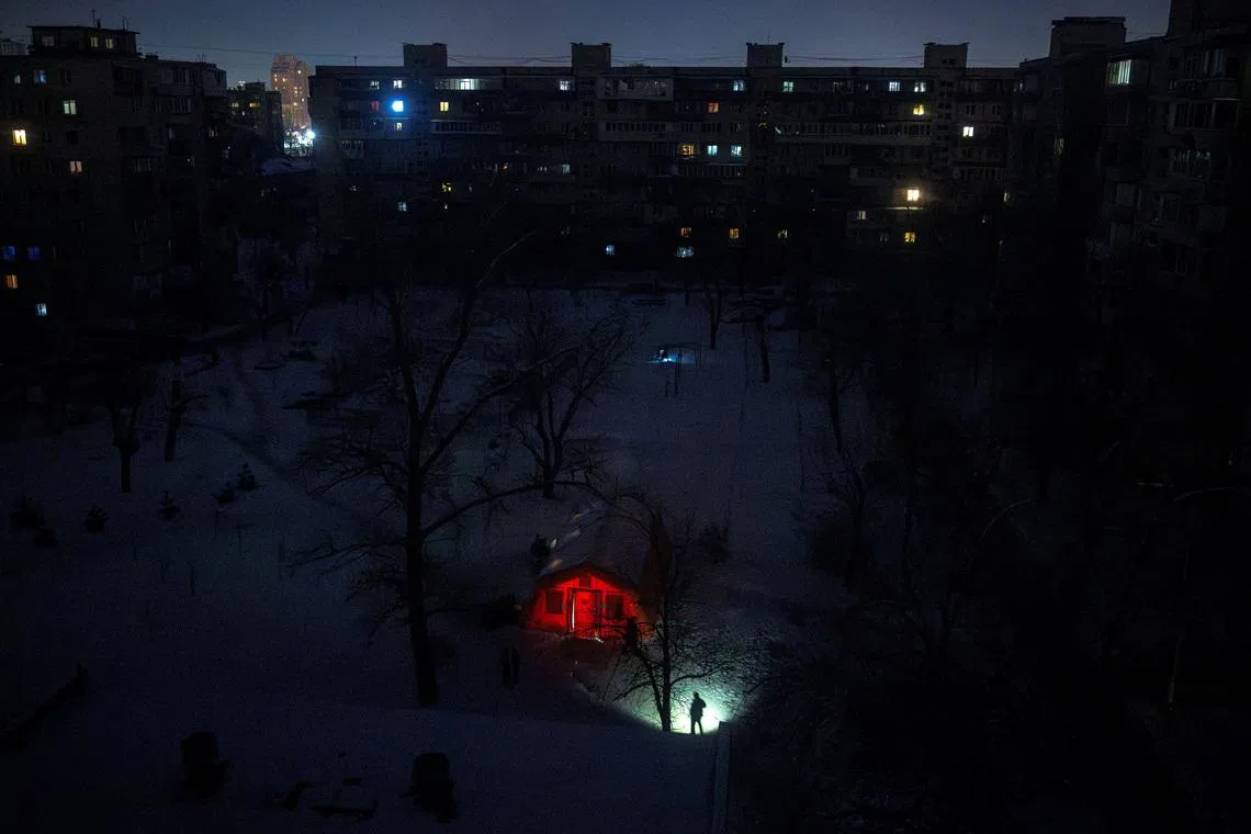 A person carrying a torch approaches a tent provided by emergency services for residents whose apartments are left without heating during sub-zero temperatures, amid Russia's attack on Ukraine, during a winter night in Kyiv, Ukraine, January 17, 2026. REUTERS/Thomas Peter