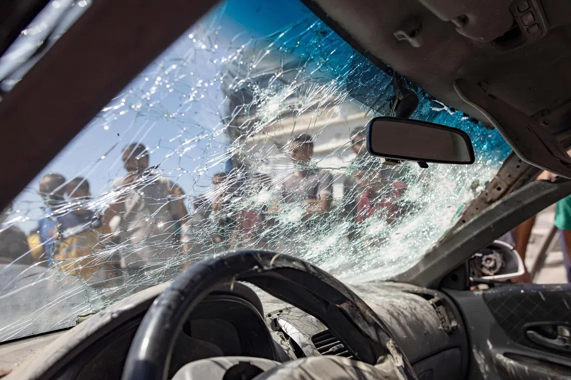 Palestinians inspect a damaged car after an Israeli air strike in the Al-Mawasi area of  Khan Yunis, southern Gaza Strip on 16 July 2024.