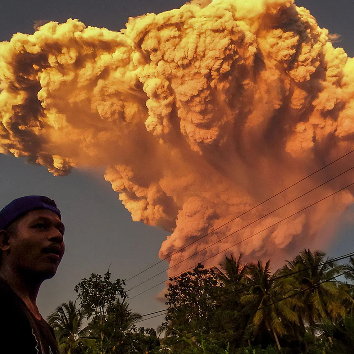 TOPSHOT - A villager watches the eruption of Mount Lewotobi Laki-Laki as seen from Talibura village in Sikka, East Nusa Tenggara, on June 17, 2025. A volcano in eastern Indonesia spewed a colossal ash tower into the sky on June 17, authorities said, after they raised its alert level to the highest of a four-tiered system. (Photo by AFP)