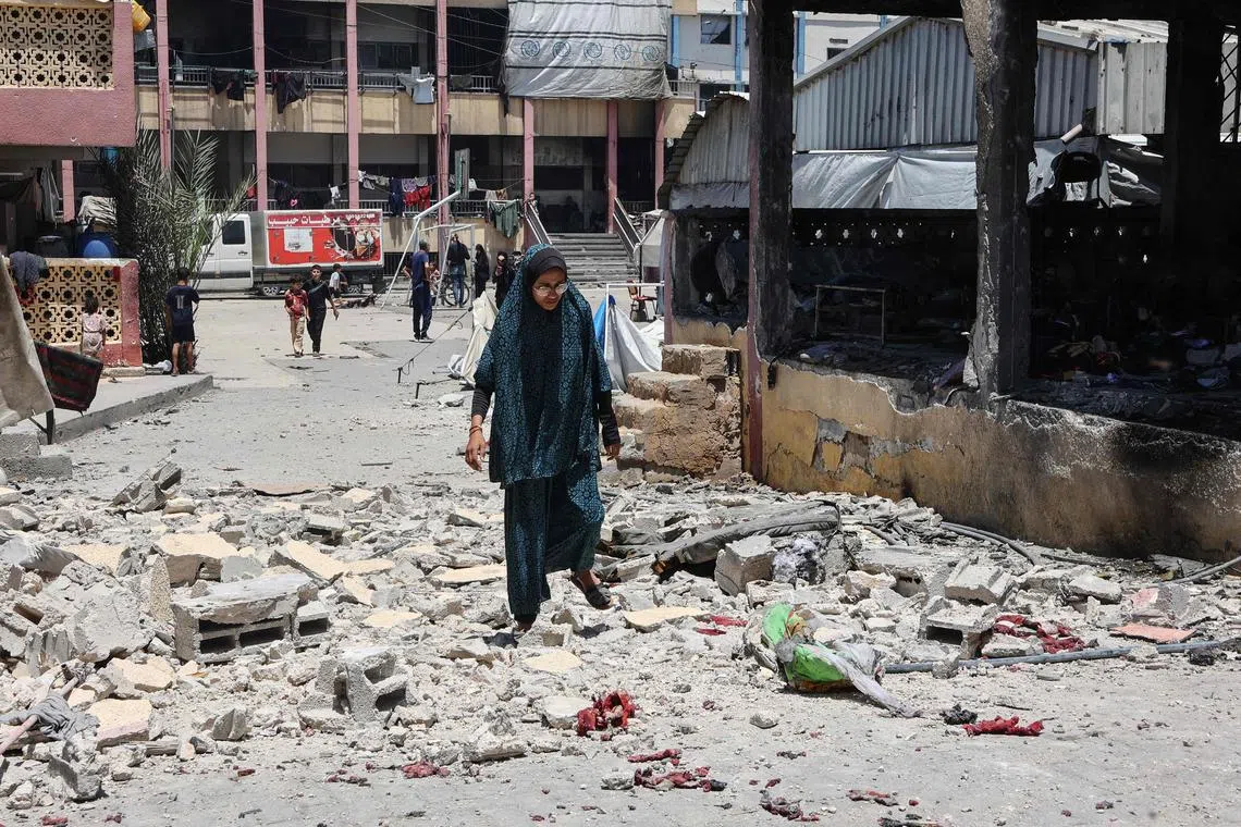 A woman walking over the debris of a school in Gaza City that was hit by an   overnight Israeli strike, on July 3.