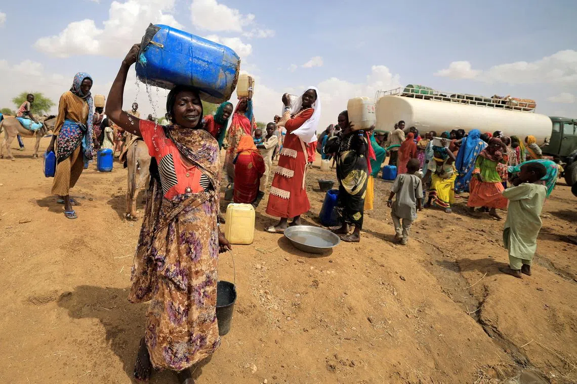 A Sudanese refugee woman, who fled the violence in Sudan's Darfur region, carrying a jerrycan of water as she walks to her makeshift shelter near the border between Sudan and Chad in Koufroun, Chad May 10.