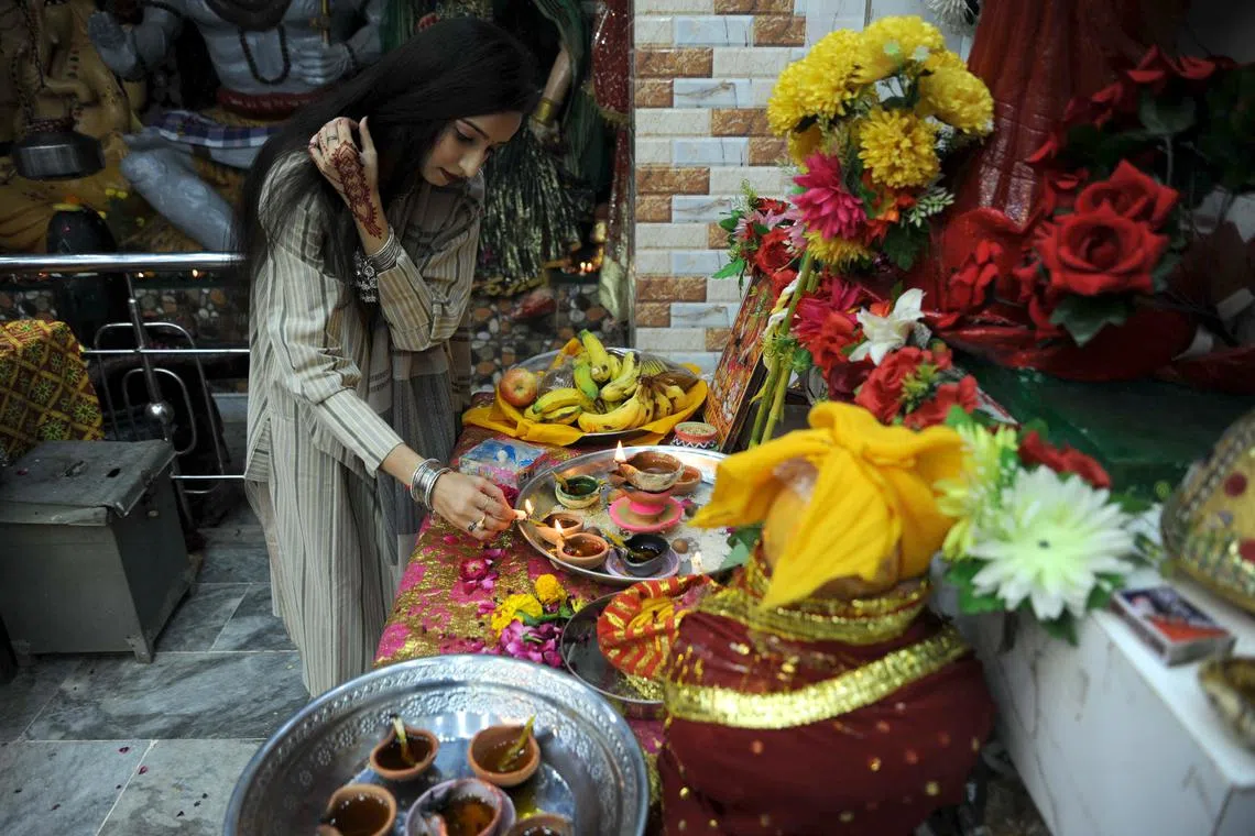 A Pakistani Hindu lighting earthen lamps to celebrate the Diwali festival in Hyderabad, Pakistan on Nov 12, 2023. 