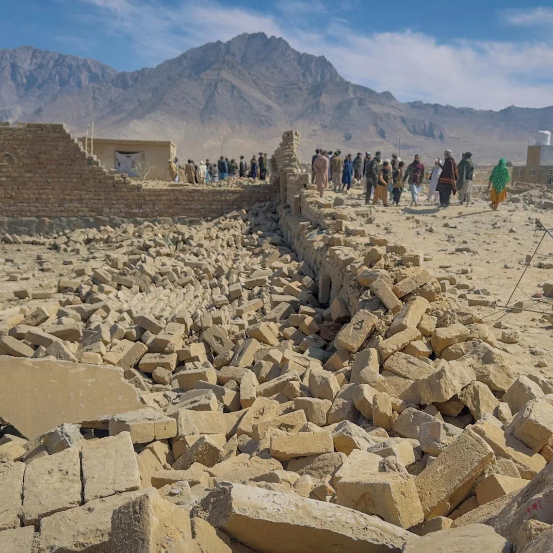 People stand near a house damaged in what the Taliban said was a Pakistani air strike on the outskirts of Kabul, Afghanistan, March 13, 2026. Picture taken with a mobile phone. REUTERS/Sayed Hassib