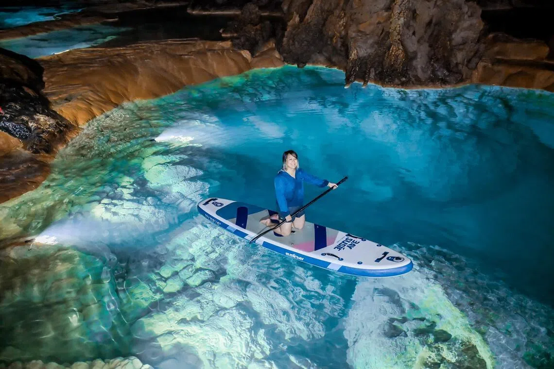 The writer tries stand-up paddleboarding in Shilong Cave, an hour from Guiyang — a highlight of Guizhou’s emerging cave tourism trend.
