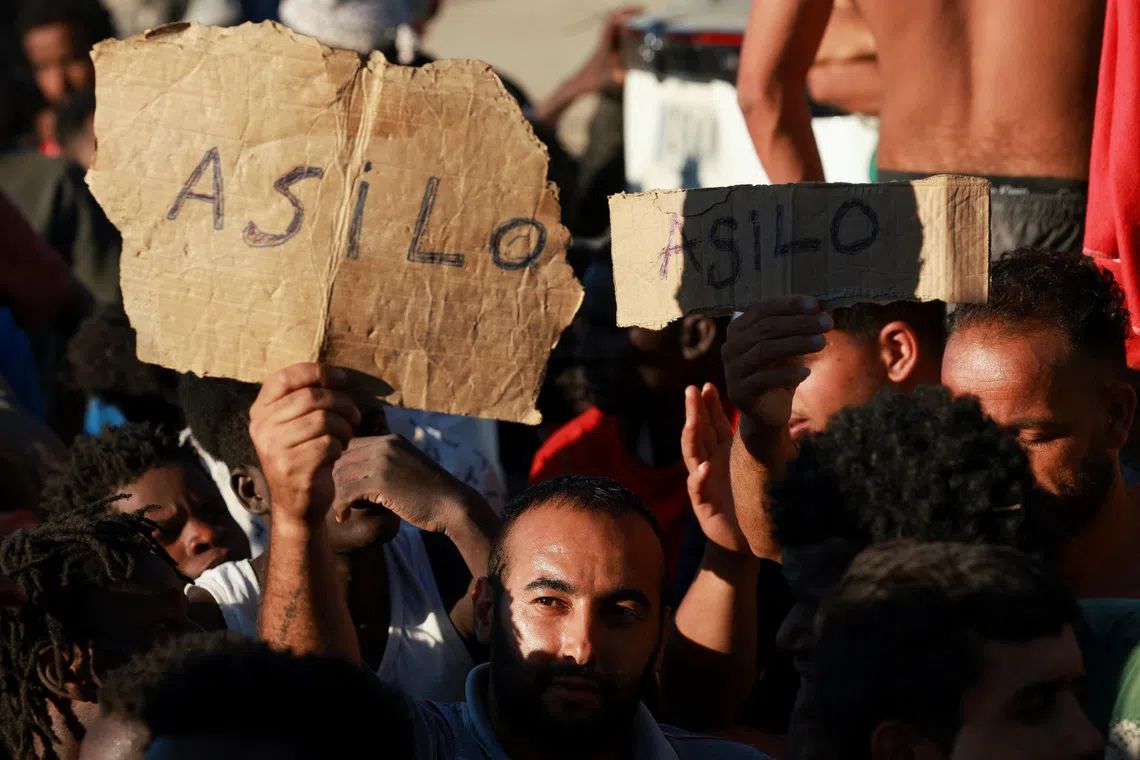 Migrants with signs reading “asylum” in Spanish in Ceuta on Aug 3.