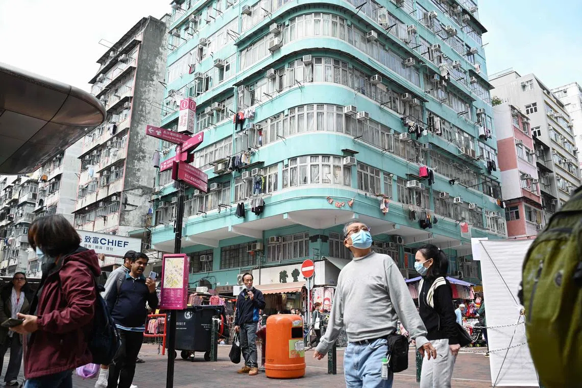 People walk through a neighbourhood in the Kowloon district of Hong Kong on February 27, 2024, a day ahead of the city's annual budget to be announced on February 28. (Photo by Peter PARKS / AFP)