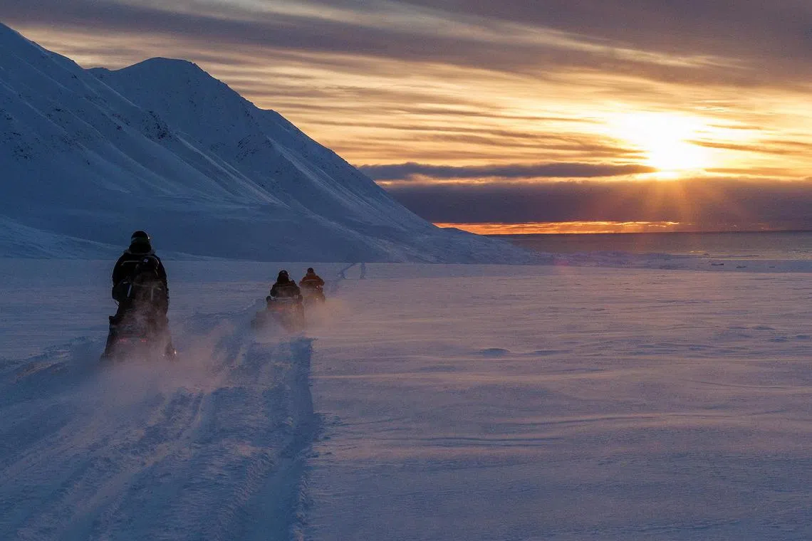 Researchers monitoring ozone depletion over the Arctic drive their snowmobiles near Svalbard in Norway.