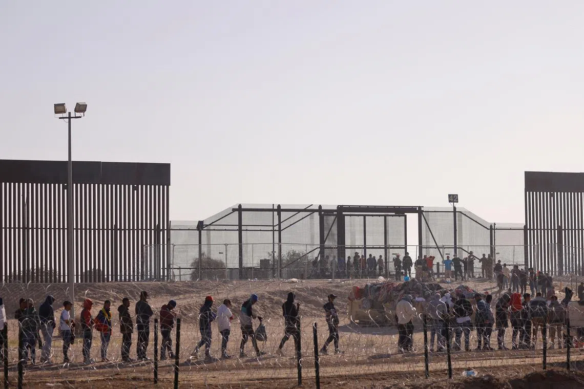 Migrants stand near the border wall after having crossed the U.S.-Mexico border to turn themselves in to U.S. Border Patrol agents, after the lifting of COVID-19 era Title 42 restrictions that have blocked migrants at the border from seeking asylum since 2020, as seen from Ciudad Juarez, Mexico May 12, 2023. REUTERS/Jose Luis Gonzalez