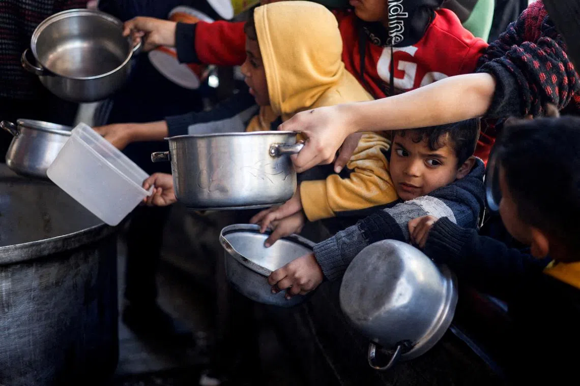 FILE PHOTO: Palestinian children wait to receive food cooked by a charity kitchen amid shortages of food supplies, as the conflict between Israel and the Palestinian Islamist group Hamas continues, in Rafah, in the southern Gaza Strip, March 5, 2024. REUTERS/Mohammed Salem/File Photo