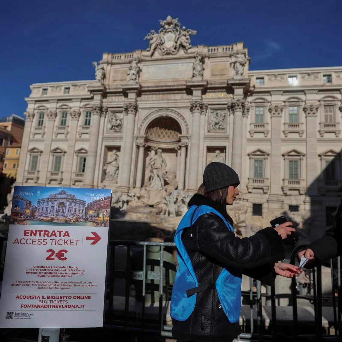 A tourist shows his two-euro ticket to access the viewing area of the Trevi Fountain in Rome, after the city introduces paid entry at several monuments and museums previously free, in Rome, Italy, February 2, 2026. REUTERS/Vincenzo Livieri