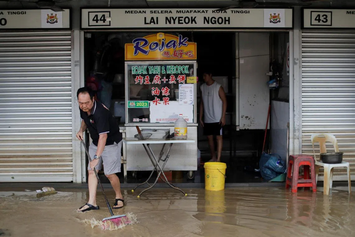 A hawker cleans his stall at a food court, as the floodwaters recede, in Kota Tinggi, Johor.