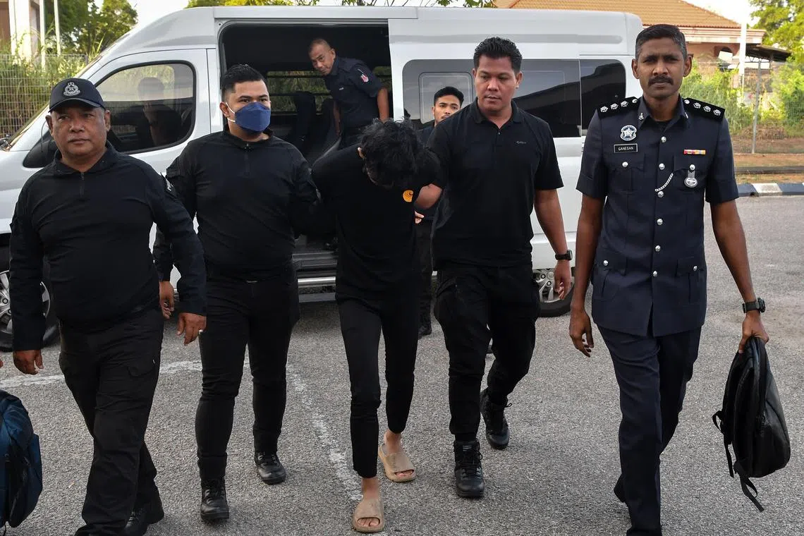 Muhammad Hazim Muhammad, 19, being escorted by police officers at the Kota Bharu Magistrate's Court, Kelantan, on May 12.