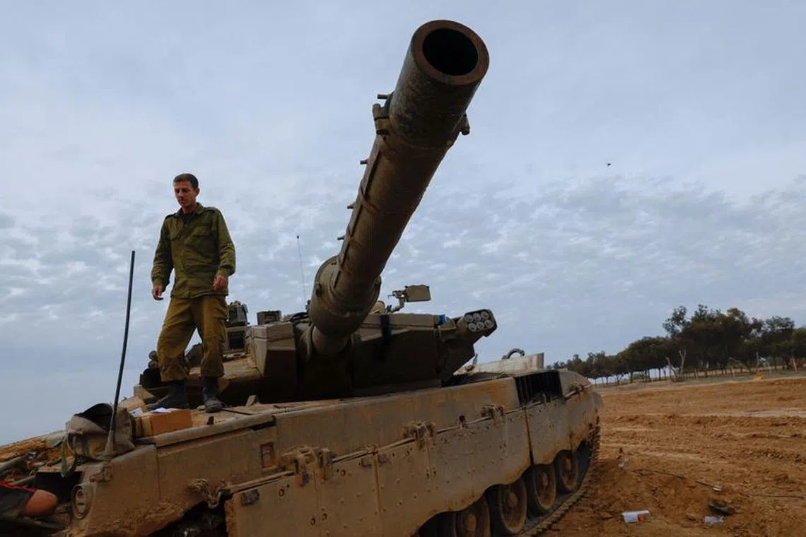 An Israeli soldier stands on a Merkava tank near the Israel-Gaza border, during a temporary truce between Hamas and Israel, in southern Israel, Nov 25, 2023. REUTERS/Alexander Ermochenko