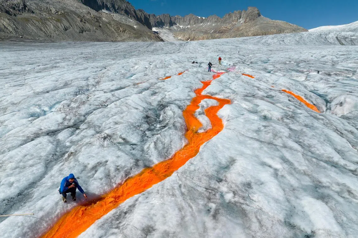 A team from ETH Zurich, a research university, using orange dye for an annual measuring of surface melt at the Rhône Glacier, which has retreated since 2007 by about half a kilometer, Aug 23, 2023. 