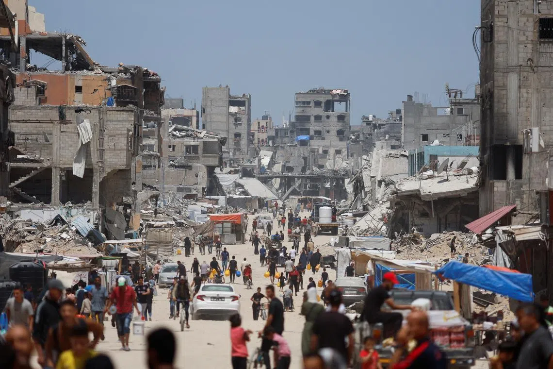 FILE PHOTO: People and vehicles pass by buildings destroyed in an Israeli strike, amid the ongoing conflict between Israel and Hamas, in Khan Younis, in the southern Gaza Strip, May 22, 2024. REUTERS/Mohammed Salem/File Photo