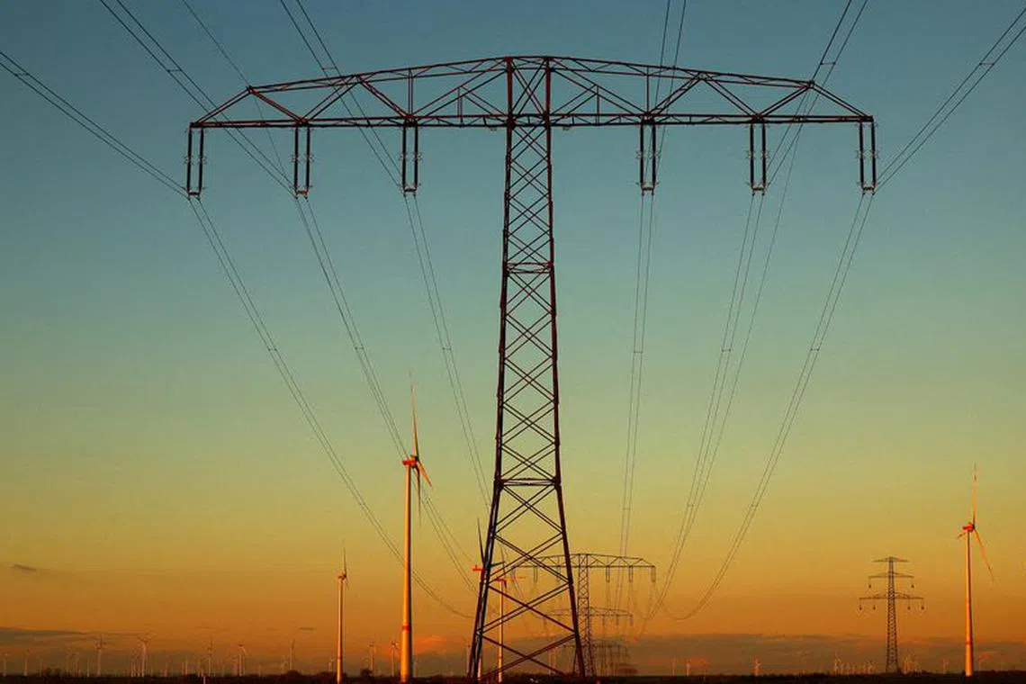 FILE PHOTO: Electrical power pylons with high-voltage power lines are seen next to wind turbines near Weselitz, Germany November 18, 2022. REUTERS/Lisi Niesner/File Photo
