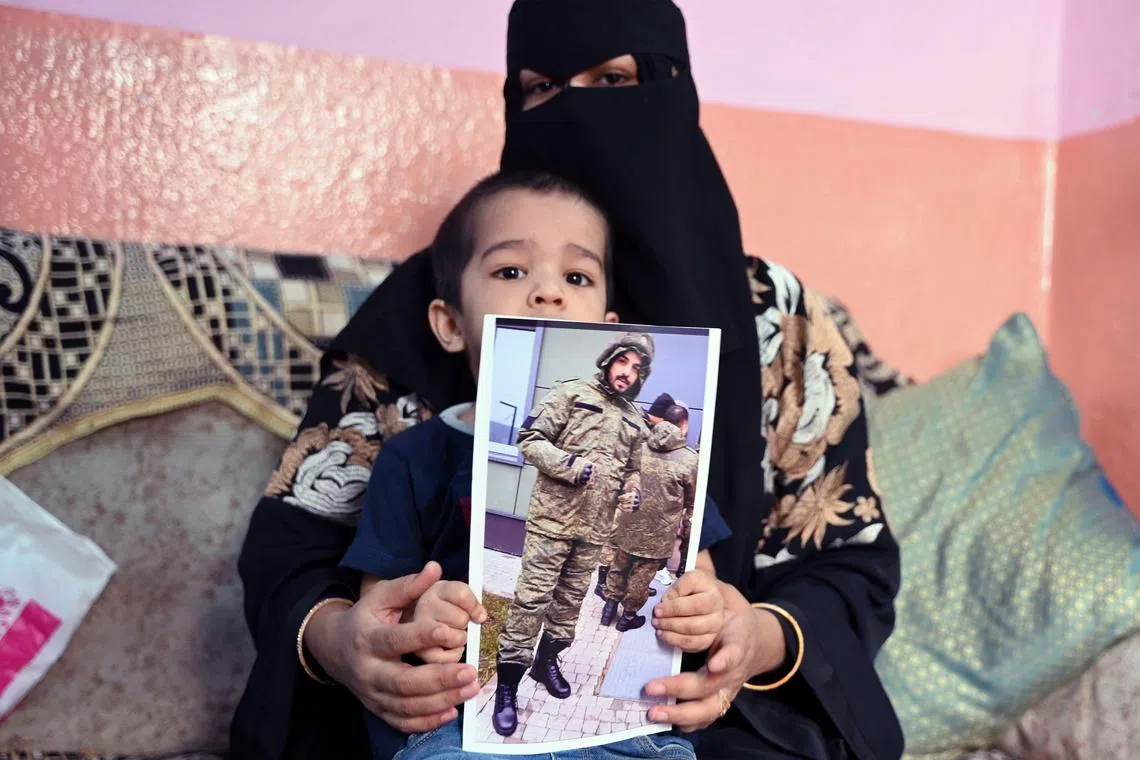 Indian national Mohammed Asfan, seen wearing Russian military fatigues who last called family from the southern Russian city of Rostov-on-Don before being deployed amid the conflict in Ukraine, being held by his wife Asma Shireen and their child in Hyderabad. 