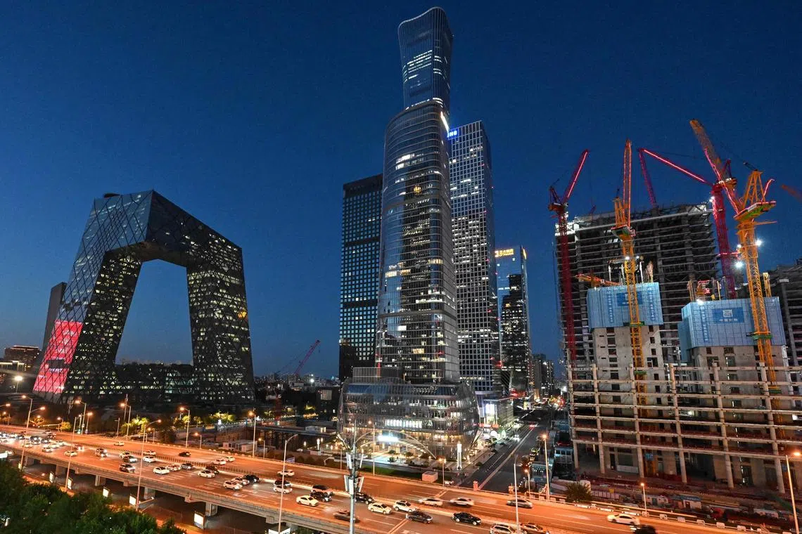 Vehicles move past illuminated CCTV tower (L) and other skyscrapers in Beijing on July 18, 2024. (Photo by ADEK BERRY / AFP)