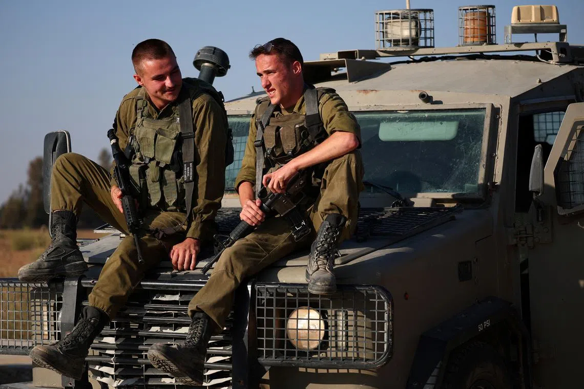 Israeli soldiers sit on a military vehicle near the Israel-Gaza border, amid the Israel-Hamas conflict, in Israel, August 23, 2024. REUTERS/Florion Goga